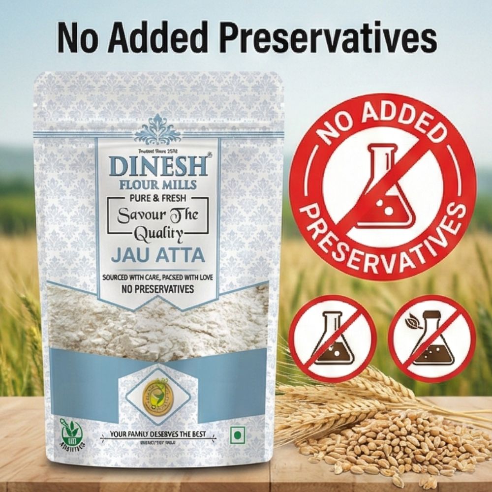 Dinesh Flour Mills Jau Atta package with no added preservatives label on a wooden surface with wheat background.