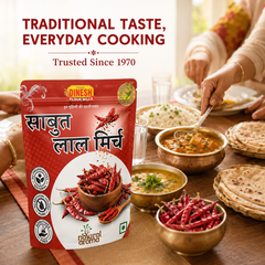A stand-up pouch of Dinesh Flour Mills Savboot Lal Mirch (spicy red chilies) is displayed on a wooden dining table surrounded by bowls of food and hands serving, with promotional text at the top.