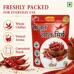 A red stand-up pouch of Dinesh Flour Mills Sabut Lal Mirch (whole red chilies) displayed on a light textured background with decorative dried red chilies. The left side features marketing text and icons highlighting 'Whole Chillies', 'Natural Aroma', and 'Convenient Pouch'.